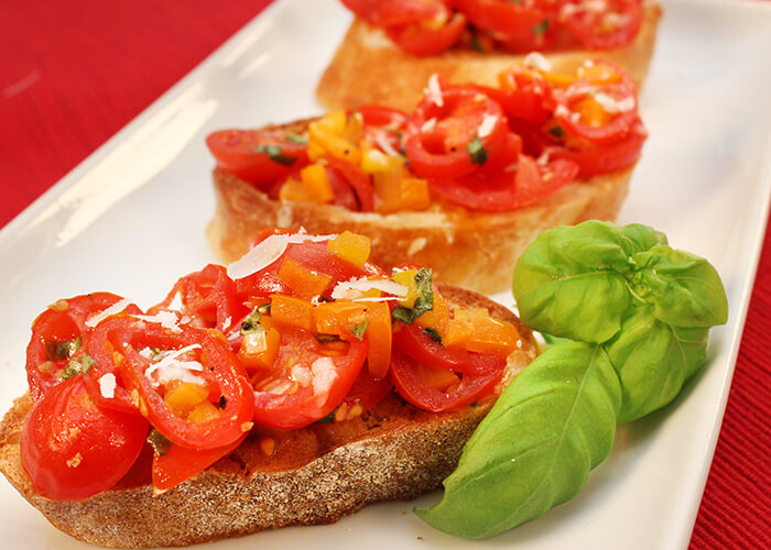 Sliced Sweetpops Tomatoes on Slices of Bread with Herbs and Cheese