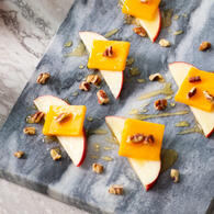Sliced SweeTango Apples topped with slices of cheddar cheese, chopped pecans and drizzled with honey.